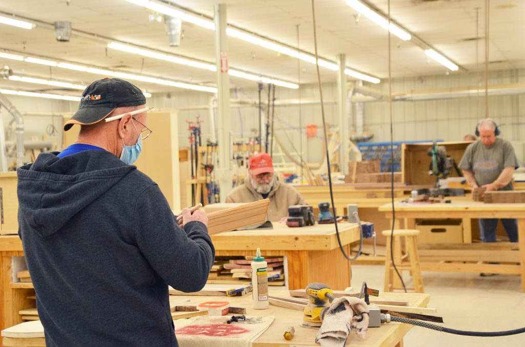 Dave Benzel (center), a retired community member, enjoys coming to the shop to build furniture for his family and friends. Matt Thun (right) is part of The DIY Woodshop staff, as well as an assistant professional. 