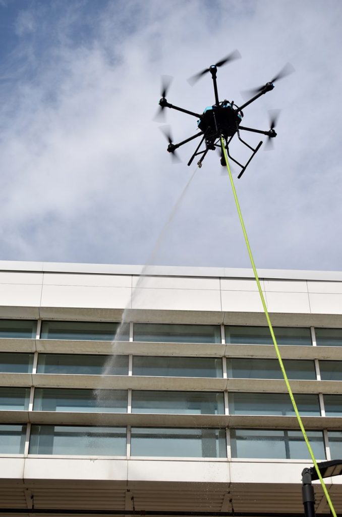 Drone pilot Justin Lee maneuvers a Drone Wash cleaning drone at Plexpod Westport Commons